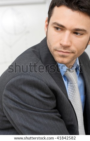 Closeup portrait of businessman wearing grey suit and blue shirt, serious look.