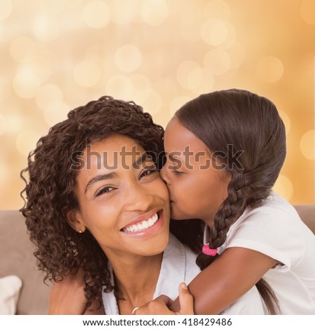 Colorful background against pretty mother sitting on the couch with her daughter smiling at camera