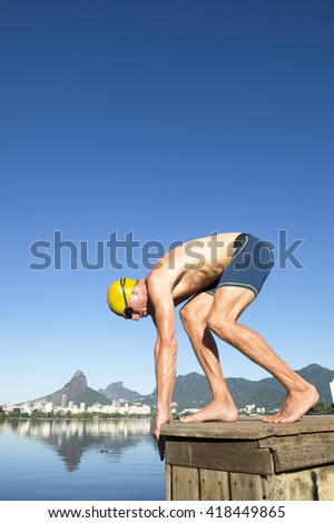 Athlete swimmer with yellow swimming cap crouching in the start position for a race at the Lagoa Rodrigo de Freitas lagoon in Rio de Janeiro, Brazil