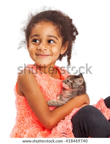 Happy mixed race four year old girl holding a kitten and looking up with a smile