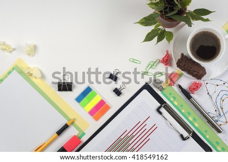 Office table desk with set of colorful supplies, white blank note pad, cup, pen, crumpled paper, flower on white background. Top view and copy space for text