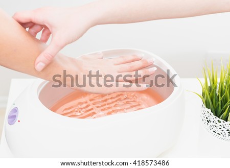 Putting hand in paraffin wax bath Royalty-Free Stock Photo #418573486
