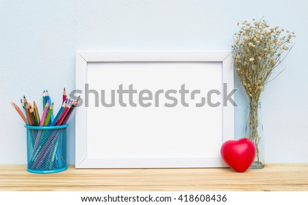 Blank frame, pencil and heart on the table, mock up