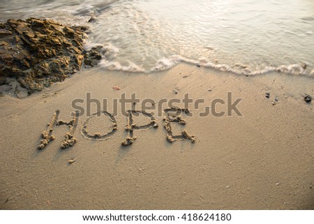 Hope written in the sand at the beach waves in the background.