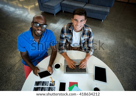 Portrait of colleagues using digital tablet and laptop in the office