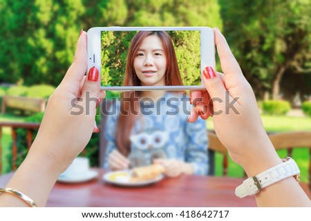 Hand woman with Smartphone taking a picture of Asia girl teenage and breakfast in the resort.