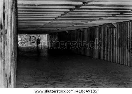 Tunnel underground pedestrian crossing with a picture of graffiti on the walls. Ideal for creative design scene. Selective focus. Black and white stylized photo film