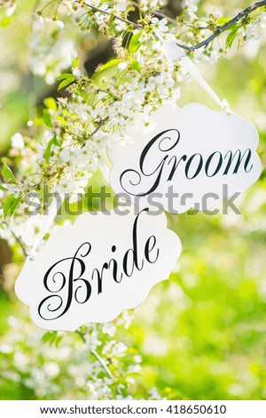 Bride and groom decoration boards handing on the blooming tree