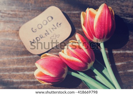 Tulips with good morning monday on paper card on wooden background