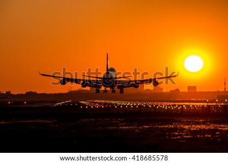 Big airplane is approaching the runway during sundown.