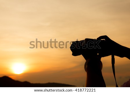 silhouette of woman hand using the digital camera take phothos when sunrise