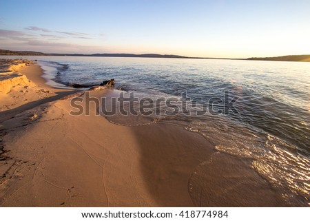 Driftwood On Lake Superior. Lake Superior beach bathed in golden light with copy space in the foreground. Pictured Rocks National Lakeshore. Munising, Michigan.