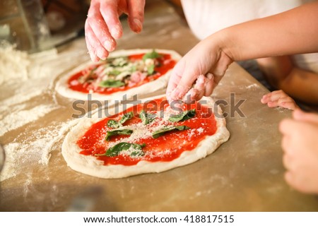 Preparing Classical Pizza Margherita. Cooks add grated parmesan cheese. Selective focus Royalty-Free Stock Photo #418817515