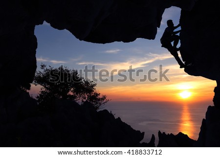 Man climbing in the cave on the mountain at sunset.