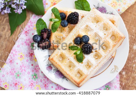 Belgian waffles with fresh berries on rustic wooden background, top view, horizontal image