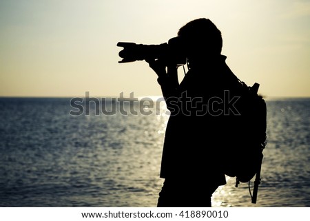 Silhouette photographer 's taking a picture at the beautiful beach with sunset