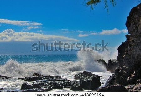 Tropical ocean beach waves breaking onto lava rocks located in beautiful travel destination Maui, Hawaii