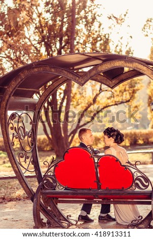 In love couple in the gazebo. The symbol of the heart. Bride and groom on the bench. A wedding in the autumn.
