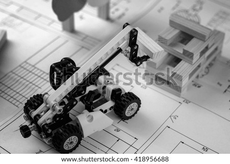 Toy construction machine builds model of house from wooden blocks (bars) at the drawings.