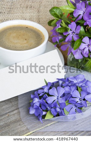 Coffee mug with Vinca flowers and notes for text. Romantic date, invitation, sweet wish concept.  toned image.