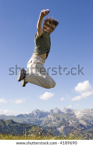 Real photo of a happy woman jumping in front of a mountain landscape. Partially motion blurred. Sella - Dolomites