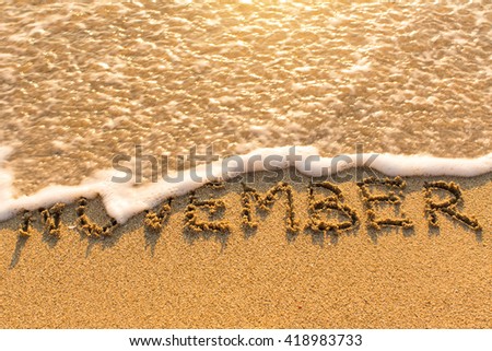 November - word drawn on the sand beach with the soft wave.