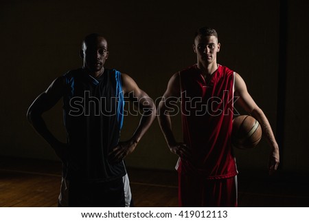Portrait of basketball players posing with hands on hips on a gym