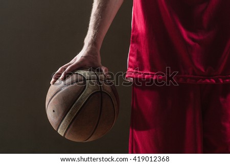 Close up on a basketball held by basketball player on a gym