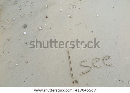 written words "I see" on sand of beach