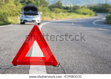 Red emergency stop sign and broken silver car on the road
