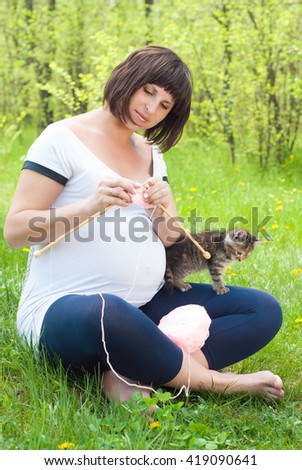 Pregnant Woman with Kitten knits in the Park in Summer. Family Concept. Healthy Lifestyle 