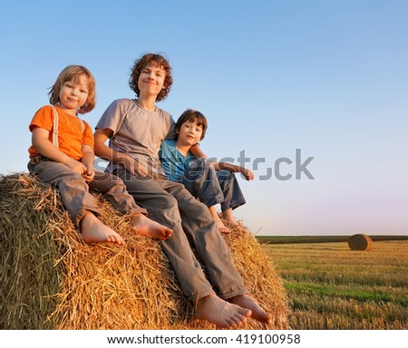 3 boys in a haystack in the field in autumn