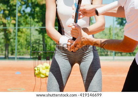 Tennis lesson - instructor showing gripping basics to female student