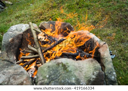 Open fire outdoors. Chic bonfire topped with stones in nature
