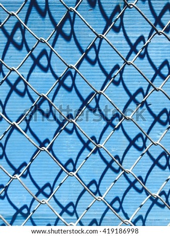 Chain Link Fence with shadow on blue background.