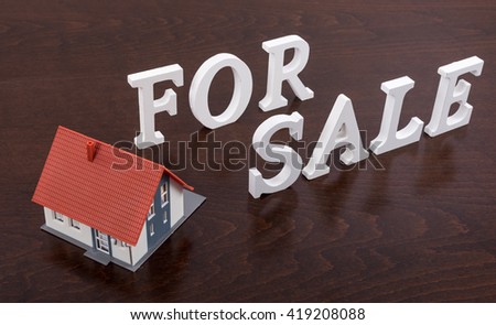 For sale sign with a house on wooden table