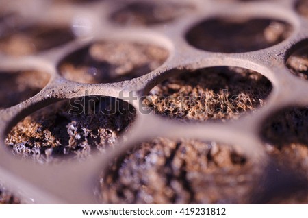 An abstract textured macro photograph,  of an ordinary object,  in the scrap yard. It has a shallow depth of field with contrasting colours. The subject is a metal grid.