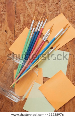Paintbrush  and post it on wood background
