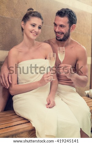 Young smiling couple relaxing in bath tub with champagne at spa