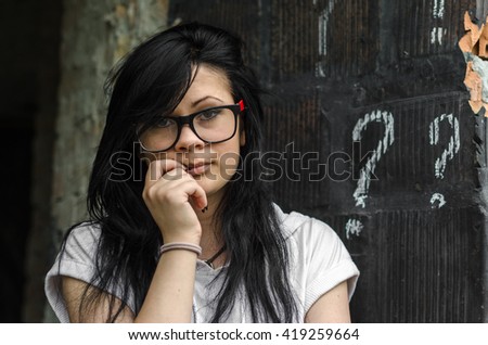Black girl standing next to a question mark sign printed on the black wall or panel