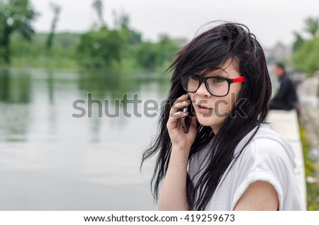 Emo girl sits by the river and talking to mobile phone