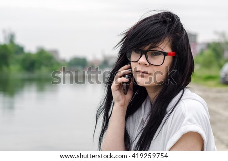 Emo girl sits by the river and talking to mobile phone