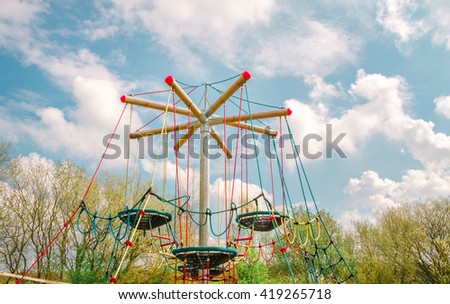 Challenging playground installation with nests and ropes for children to clamber. General view with copy space on springtime sky.