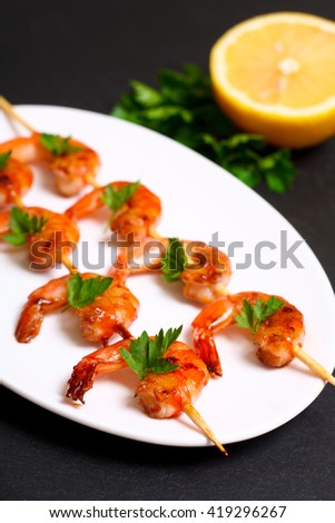 shrimps on the skewers on black background.
