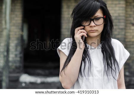 Emo girl talking on the phone in front of the old house
