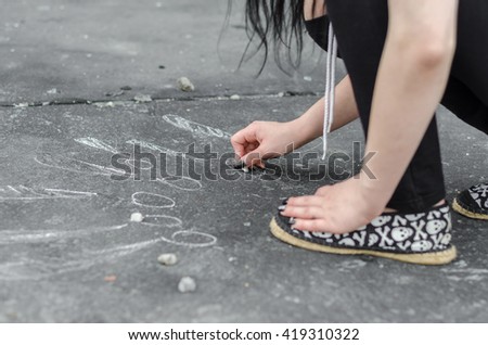 Teenage girl draws on the floor with chalk signs
