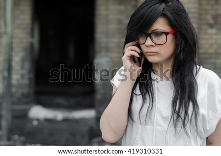 Emo girl talking on the phone in front of the old house