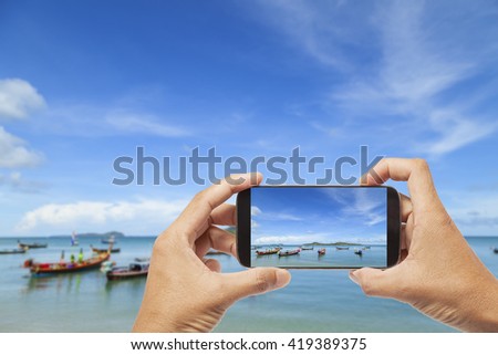 hand male Asian holding smartphone taking picture of beautiful beach,and sea  blue sky  background