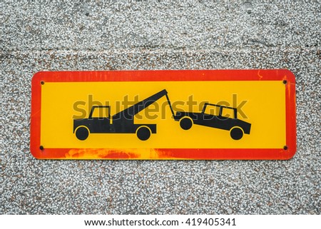 Car removal sign in yellow and red on a concrete wall