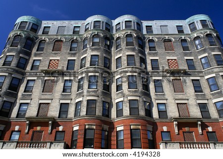 subtle yet ornate apartment house in downtown cambridge massachusetts with checker board designs and round corners against a deep blue sky